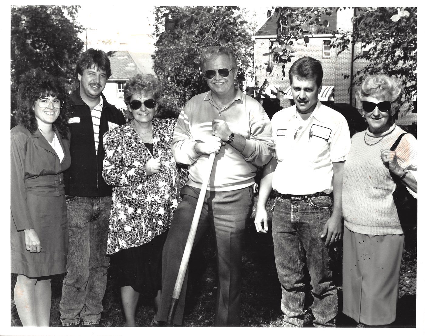 Black-and-white photo of two generations of the family breaking ground at the 3301 Mt. Vernon Avenue building, one holding a shovel